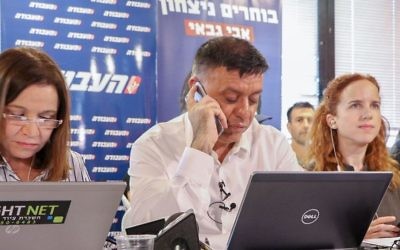 Flanked by former party boss Shelly Yachimovich (left) and Labor lawmaker Stav Shaffir, Avi Gabbay (C), one of two candidates for the Labour Party leadership, phones potential voters ahead of the second round of the party primaries in Tel Aviv, July 9, 2017. (Flash90)