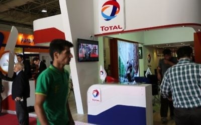 People stroll past the stand of French oil and gas company Total during Iran's annual International Oil, Gas, Refining & Petrochemical Exhibition in Tehran, May 6, 2015. (AFP PHOTO / ATTA KENARE) People stroll past the stand of French oil and gas company Total during Iran's annual International Oil, Gas, Refining & Petrochemical Exhibition in Tehran, May 6, 2015. (AFP PHOTO / ATTA KENARE)