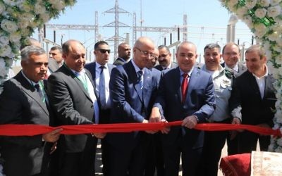 Israel's National Infrastructure Minister Yuval Steinitz (wearing red tie) and Palestinian Authority Prime Minister Rami Hamdallah cut the ribbon to mark the first ever commercial agreement between the Israeli and Palestinian energy companies to increase provision in the West Bank area of Jenin, July 10, 2017. Yoav Mordechai, Coordinator of Government Activities in the Territories, stands behind Steinitz,with Yiftach Ron Tal, Israel Electric Corporation head, on the far right.(Yossi Weiss).