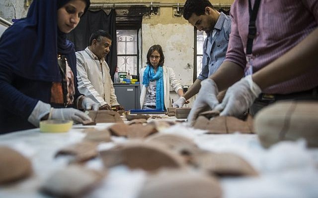 French Anita Quiles, a researcher in the French Institute of Eastern Archaeology (IFAO) in Cairo, stands near local staff at a dating laboratory inside the institute on May 14, 2017. (AFP PHOTO / KHALED DESOUKI)