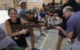Foreign tourists train with a wooden gun as they participate in a two hour anti-terror course at the Caliber 3 shooting range, near the West Bank settlement of Efrat on July 18, 2017. (AFP PHOTO / MENAHEM KAHANA)