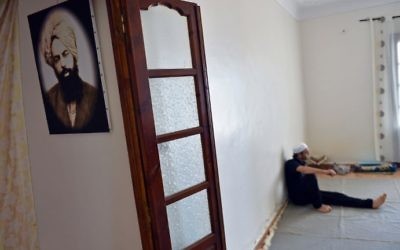 A member of Algeria's small Ahmadi community sits at a house in Tilpasi, west of Algiers, near a photo of Mirza Ghulam Ahmad, the founder of the Ahmadiyya movement, on June 30, 2017. (AFP Photo/Ryad Kramdi)