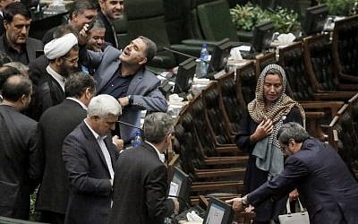 An Iranian MP (C) uses a cell phone to take a "selfie" picture as EU foreign policy chief Federica Mogherini walks by during the ceremony for the swearing in of Iran's President during an official ceremony before parliament in Tehran, on August 5, 2017. (AFP PHOTO / ATTA KENARE)