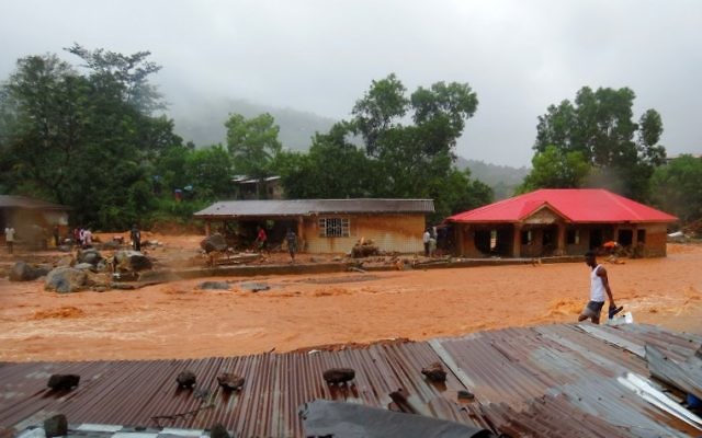 A resident walks through floodwaters past a damaged building in an area of Freetown on August 14, 2017, after landslides struck the capital of the west African state of Sierra Leone. (AFP PHOTO / SAIDU BAH) A resident walks through floodwaters past a damaged building in an area of Freetown on August 14, 2017, after landslides struck the capital of the west African state of Sierra Leone. (AFP PHOTO / SAIDU BAH)