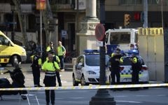 Medical staff and policemen stand in a cordoned-off area after a van plowed into the crowd, injuring several people, in Barcelona on August 17, 2017. (AFP/Josep Lago)