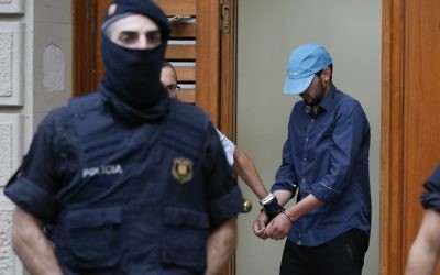 Catalan autonomous police officers, known as Mosso d'Esquadra, detain a cuffed suspect in Ripoll during a search linked to the deadly terror attacks in Barcelona and the seaside resort of Cambrils on August 18, 2017, a day after a van plowed into the crowd, killing 14 people and injuring over 100 on the Rambla in Barcelona. 
(AFP PHOTO / PAU BARRENA)
