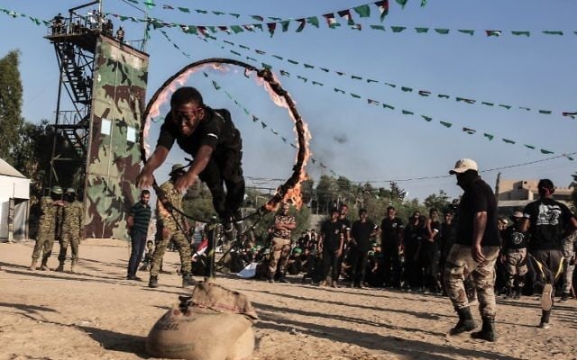 Young Palestinians jump though a ring of fire during a military graduation ceremony at a Hamas summer camp in Khan Yunis, in the southern Gaza Strip, on August 18, 2017. ( AFP PHOTO / SAID KHATIB)