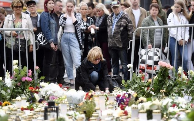 Candles and flowers are left at the makeshift memorial by well wishers for the victims of Friday's stabbings at the Turku Market Square, Finland on August 19, 2017. (AFP Photo/Lehtikuva/Vesa Moilanen)