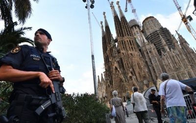 A police officer stands by the Sagrada Familia basilica in Barcelona on August 20, 2017, before a mass to commemorate victims of two devastating terror attacks in Barcelona and Cambrils. (AFP PHOTO / PASCAL GUYOT)