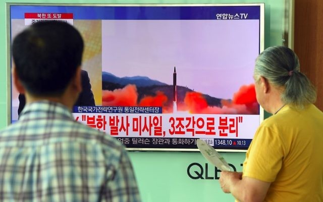 People watch a television news screen showing file footage of a North Korean missile launch, at a railway station in Seoul on August 29, 2017. AFP PHOTO / JUNG Yeon-Je)