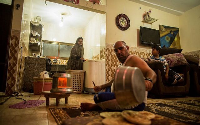 This photo taken on July 12, 2017 shows a Palestinian man preparing bread as his wife washes clothes during the few hours of mains electricity they receive every day, at the al-Shati refugee camp in Gaza City. (AFP PHOTO / MAHMUD HAMS)