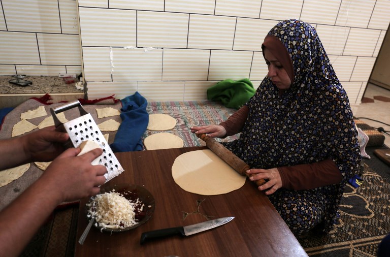This photo taken on August 3, 2017 shows a Palestinian woman preparing bread during the few hours of mains electricity supply they receive every day, at Rafah refugee camp in the southern Gaza Strip. (AFP PHOTO / SAID KHATIB)