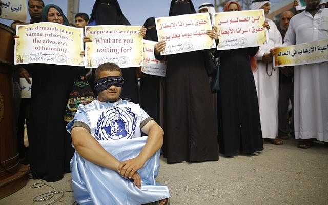 Palestinians block the road ahead of a convoy transporting United Nations Secretary General Antonio Guterres, upon his arrival at Erez border crossing in Beit Hanun, in the northern Gaza Strip, on August 30, 2017. Arabic writing on placards reads: "Where is the world from the rights of our heroic prisoners?" / AFP PHOTO / MOHAMMED ABED