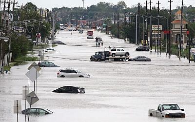 A car gets towed while men walk in the flooded waters of Telephone Rd. in Houston, Texas on August 30, 2017. (AFP PHOTO / Thomas B. Shea)