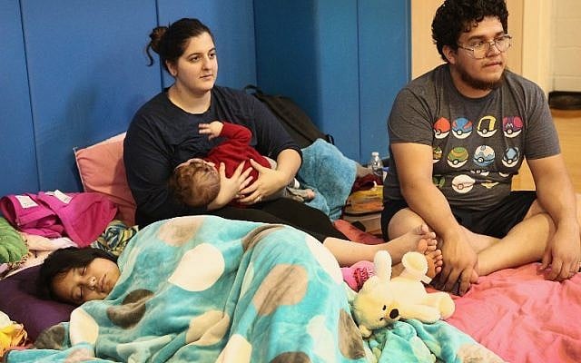 CHANNELVIEW, TX - AUGUST 29: Arzu and Gerardo Vargas relax with their children in the Channelview High School gym which has been turned in to an evacuation shelter for victims of flooding following Hurricane Harvey on August 29, 2017 in Channelview, Texas. Harvey, which made landfall north of Corpus Christi August 25, has dumped nearly 50 inches of rain in and around Houston. Scott Olson/Getty Images/AFP