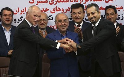 Chief Competitive Officer of Groupe Renault Thierry Bolloré, left, Chairman of Industrial Development and Renovation Organization of Iran, IDRO, Mansour Moazami, center, and Negin Group CEO Kourosh Morshed Solouk join hands after signing a deal in Tehran, Iran, Monday, Aug. 7, 2017. (AP Photo/Vahid Salemi)