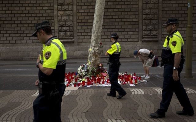 Spanish police officers walk past candles and flowers placed on the ground after a terror attack that killed 14 people and wounded over 120 in Barcelona, Spain, August 20, 2017. (AP/Emilio Morenatti) Spanish police officers walk past candles and flowers placed on the ground after a terror attack that killed 14 people and wounded over 120 in Barcelona, Spain, August 20, 2017. (AP/Emilio Morenatti)
