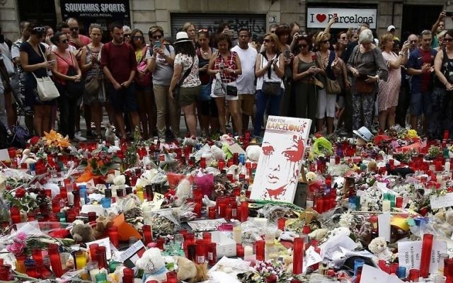 People stand next to candles and flowers placed on the ground after a terror attack that killed 14 people and wounded over 120 in Barcelona, Spain, Sunday, Aug. 20, 2017. (AP Photo/Manu Fernandez) People stand next to candles and flowers placed on the ground after a terror attack that killed 14 people and wounded over 120 in Barcelona, Spain, Sunday, Aug. 20, 2017. (AP Photo/Manu Fernandez)