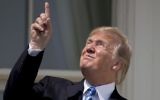 US President Donald Trump points to the sun as he arrives to view the solar eclipse, on August 21, 2017, at the White House in Washington. (AP Photo/Andrew Harnik)