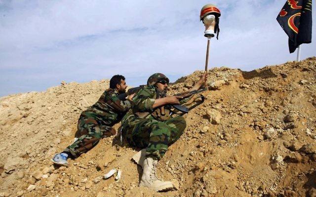 In this Nov. 22, 2013 file photo, Iraqi and Lebanese Shiite fighters from a group called the Hussein Brigade use a helmet to draw sniper fire, during clashes with the Sunni-dominated Free Syrian Army, in the town of Hejeira, near Damascus, Syria. (AP Photo/Jaber al-Helo, File) In this Nov. 22, 2013 file photo, Iraqi and Lebanese Shiite fighters from a group called the Hussein Brigade use a helmet to draw sniper fire, during clashes with the Sunni-dominated Free Syrian Army, in the town of Hejeira, near Damascus, Syria. (AP Photo/Jaber al-Helo, File)
