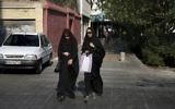 In this Thursday, Aug. 24, 2017, photo, two Iranian women cross a street while wearing the "chador," a head-to-toe garment, in downtown Tehran, Iran. (AP Photo/Vahid Salemi)