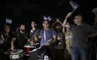 Menny Naftali, center, and Eldad Yaniv, far right, the main organizers of a weekly protest against Prime Minister Benjamin Netanyahu, in front of the home of Attorney General Avichai Mandelblit in Petah Tikva, August 26, 2017.  (AP Photo/Dan Balilty)