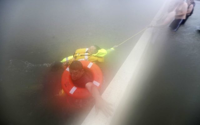 Wilford Martinez, bottom, grabs the median as he is rescued from his flooded car along Interstate 610 in floodwaters from Tropical Storm Harvey, August 27, 2017, in Houston. (AP Photo/David J. Phillip) Wilford Martinez, bottom, grabs the median as he is rescued from his flooded car along Interstate 610 in floodwaters from Tropical Storm Harvey, August 27, 2017, in Houston. (AP Photo/David J. Phillip)