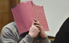 In this Feb. 26, 2015 photo former nurse Niels Hoegel., accused of multiple murder and attempted murder of patients, covering his face with a file at the district court in Oldenburg, Germany.  (Carmen Jaspersen/dpa via AP)