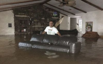 This Sunday, August 27, 2017, photo provided by Ramit Plushnick-Masti, shows her husband, Rafi, standing in waist-high water inside their flooded home in Houston's Meyerland neighborhood that was caused by Tropical Storm Harvey.  (Ramit Plushnick-Masti via AP)