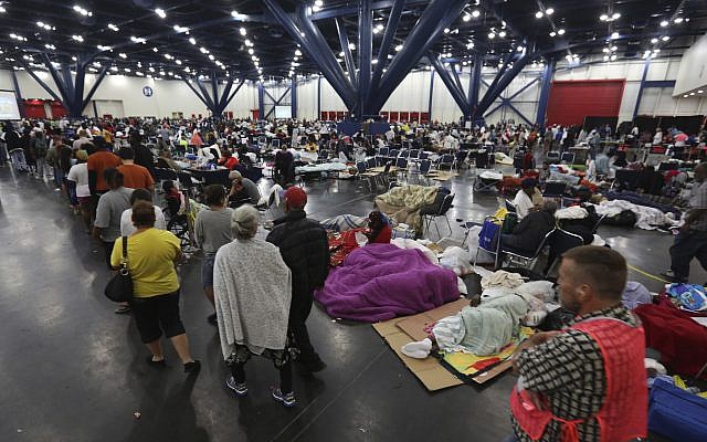 People line up for food as others rest at the George R. Brown Convention Center that has been set up as a shelter for evacuees escaping the floodwaters from Tropical Storm Harvey in Houston, Texas, Tuesday, Aug. 29, 2017. (AP Photo/LM Otero)
