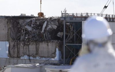 In this Feb. 10, 2016 file photo, a member of the media tour group wearing a protective suit and a mask looks at the No. 3 reactor building at Tokyo Electric Power Co's (TEPCO) tsunami-crippled Fukushima Dai-ichi nuclear power plant in Okuma, Fukushima Prefecture, northeastern Japan. (Toru Hanai/Pool Photo via AP, File)