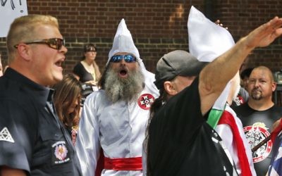 Members of the KKK are escorted by police past a large group of protesters during a KKK rally Saturday, July 8, 2017, in Charlottesville, Virginia. (AP Photo/Steve Helber)