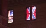 This Aug. 17, 2017 image from video shows a Confederate flag, right, displayed alongside an Israeli flag and a colonial-era American one in the seventh-floor windows of an apartment in the East Village neighborhood of New York. (PIX11 News via AP)