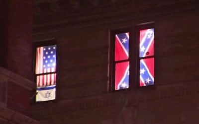 This Aug. 17, 2017 image from video shows a Confederate flag, right, displayed alongside an Israeli flag and a colonial-era American one in the seventh-floor windows of an apartment in the East Village neighborhood of New York. (PIX11 News via AP)