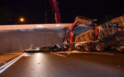 Rescue workers and police at the scene where part of a pedestrian bridge collapsed on a truck on Highway 4 near Givat Shmuel, August 14, 2017. (Moti arelitz/Flash90)