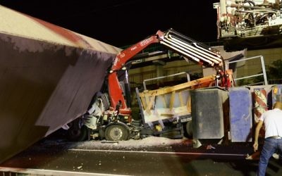 Rescue workers and police at the scene of where part of a pedestrian bridge collapsed onto a truck on Route 4 near Givat Shmuel, August 14, 2017. (Moti Karelitz/Flash90)