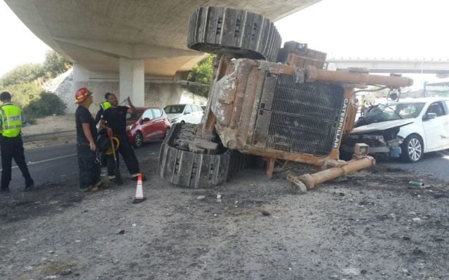 A bulldozer that was knocked off the back of a truck as it passed under a bridge on Route 1, August 21, 2017. (Israel Police) A bulldozer that was knocked off the back of a truck as it passed under a bridge on Route 1, August 21, 2017. (Israel Police)