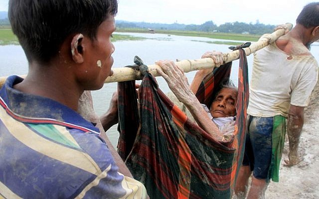 Rohingya refugees carry an elderly woman from Rakhine state in Myanmar along a path near Teknaf in Bangladesh on September 3, 2017. (AFP PHOTO / R. ASAD) Rohingya refugees carry an elderly woman from Rakhine state in Myanmar along a path near Teknaf in Bangladesh on September 3, 2017. (AFP PHOTO / R. ASAD)
