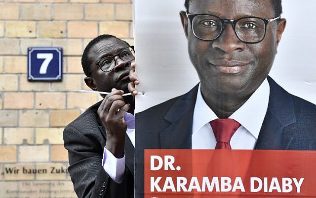 Senegalese-born German MP for the Social Democratic Party (SPD) Karamba Diaby puts up a campaign poster in Halle on September 6, 2017. (AFP/ John MACDOUGALL) Senegalese-born German MP for the Social Democratic Party (SPD) Karamba Diaby puts up a campaign poster in Halle on September 6, 2017. (AFP/ John MACDOUGALL)