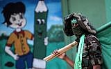 Illustrative: A masked youth cadet from the armed wing of the Hamas terror group carries the movement's flag at a march in the southern Gaza Strip city of Khan Yunis on September 15, 2017.(AFP PHOTO / SAID KHATIB)