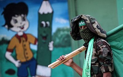 Illustrative: A masked youth cadet from the armed wing of the Hamas terror group carries the movement's flag at a march in the southern Gaza Strip city of Khan Yunis on September 15, 2017.(AFP PHOTO / SAID KHATIB)