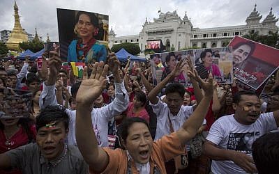 People hold the Myanmar national flag and placards as they attend a public gathering to listen to the live speech of Myanmar's State Counselor Aung San Suu Kyi in front of City Hall in Yangon on September 19, 2017. (AFP PHOTO/AUNG Kyaw Htet)