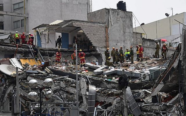 Rescuers from Mexico and Israel (olive green) search for survivors in a flattened building in Mexico City on September 21, 2017 two days after a strong quake hit central Mexico.  (AFP / Ronaldo SCHEMIDT)