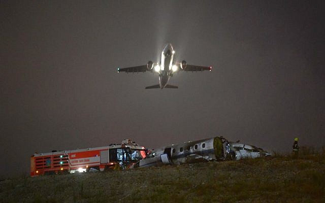 A plane passes as firefighters attempt to extinguish a burning private airplane that crashed at Ataturk Airport on September 21, 2017 in Istanbul. (AFP PHOTO / OZAN KOSE) A plane passes as firefighters attempt to extinguish a burning private airplane that crashed at Ataturk Airport on September 21, 2017 in Istanbul. (AFP PHOTO / OZAN KOSE)