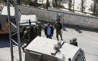A picture taken on September 26, 2017 in the West Bank village of Bayt Surik shows Israeli soldiers arresting a Palestinian, reportedly the brother of the terrorist who killed three Israelis in Har Adar. (AFP PHOTO / ABBAS MOMANI)