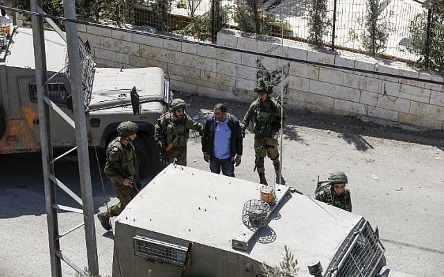 A picture taken on September 26, 2017 in the West Bank village of Bayt Surik shows Israeli soldiers arresting a Palestinian, reportedly the brother of the terrorist who killed three Israelis in Har Adar. (AFP PHOTO / ABBAS MOMANI)