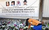 This file photo taken on March 25, 2012, in Toulouse, southwestern France, shows France's Jewish scout placing flowers under a banner paying tribute to the victims of jihadist Mohammed Merah who killed three children and a teacher at the 'Ozar Hatorah' Jewish school. (AFP/Eric Cabanis)