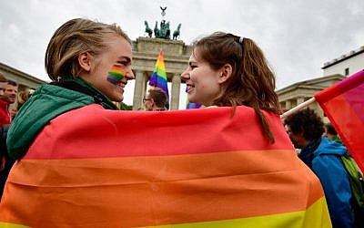 This file photo taken on June 30, 2017, shows two young women wrapped into a rainbow flag at a rally of gays and lesbians in front of the Brandenburg Gate in Berlin. (AFP Photo/Tobias Schwarz)