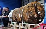 Disposers Dieter Schwaetzler, left, and Rene Bennert sit next to 1.8 ton WWII bomb right after they defused it, in Frankfurt, Germany, Sunday, Sept. 3, 2017. (AP/Michael Probst)
