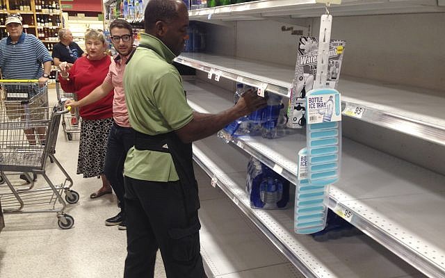 An employee restocks bottled water on bare shelves as customers look on at a Publix grocery store, September 5, 2017, in Surfside, Florida. (AP Photo/Wilfredo Lee) An employee restocks bottled water on bare shelves as customers look on at a Publix grocery store, September 5, 2017, in Surfside, Florida. (AP Photo/Wilfredo Lee)
